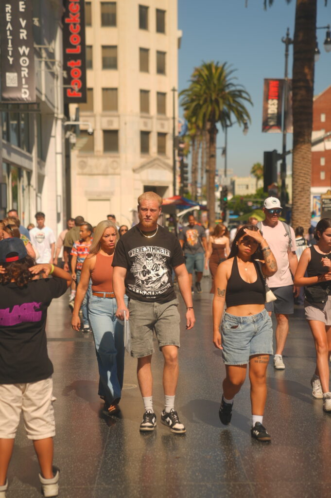 Street crowd on Hollywood Boulevard with a man in focus wearing a black graphic t-shirt.