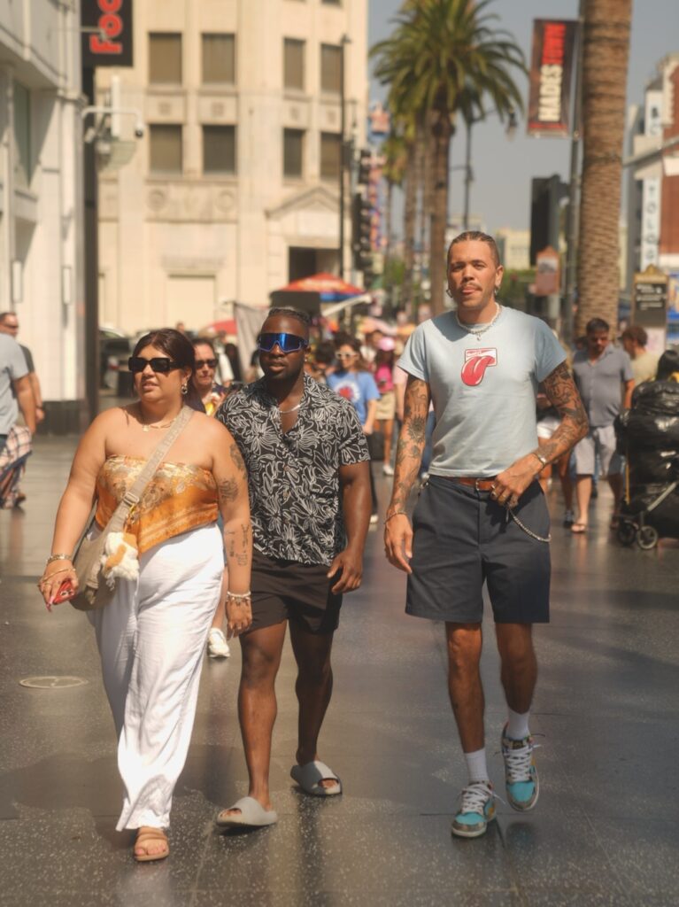 Group of three friends walking down Hollywood Boulevard, sunny LA day.