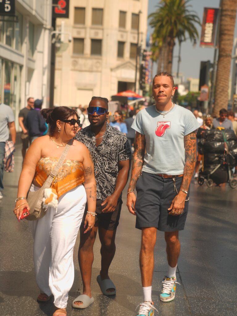 Friends walking in Hollywood, man with tattoos in light blue Rolling Stones shirt